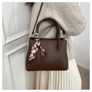 Detail of dark brown lychee leather tote with decorative silk scarf on the handles