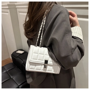 Close-up of white quilted crossbody bag with silver chain and metal twist lock