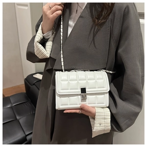 Quilted white crossbody bag with chain strap shown on a model in a stylish outfit