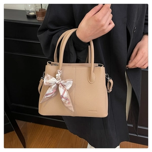 Detail of lychee textured tote bag with decorative silk scarf on handle and shoulder strap