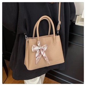 Detail of khaki leather bucket bag with printed silk scarf and adjustable strap