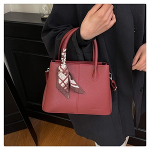 Detail of wine red pebble leather tote bag with printed silk scarf on the handle