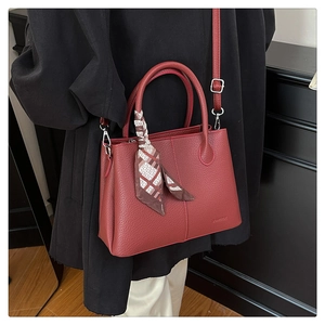 Detail of dark red lychee grain leather tote bag with decorative patterned silk scarf