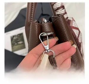 Macro shot of silver metal buckles and printed silk scarf detail on dark brown tote bag