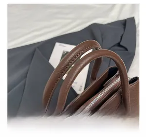 Detail of reinforced handles and floral silk scarf on dark brown litchi grain tote bag