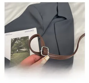 Close-up of the adjustable brown leather strap with silver metal buckle on the handbag