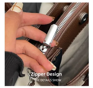 Detail showing smooth silver metal zipper on dark brown lychee grain leather bag