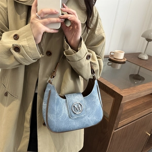 Light blue crescent handbag with brown leather trim and silver metal M logo buckle