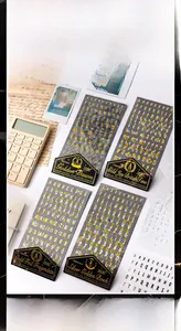 Macro shot of gold and silver foil alphabet stickers on dark marble background
