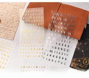 Detail showing metallic gold and silver PET letter stickers on a vintage notebook