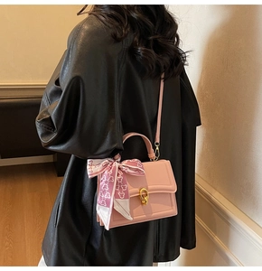 Dettaglio borsa a tracolla quadrata rosa chiaro con chiusura dorata e sciarpa di seta decorativa