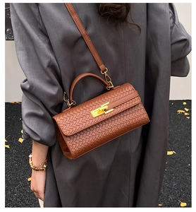 Detailed view of brown woven texture handbag featuring a golden swivel lock and leather strap