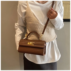 Brown woven texture handbag with gold twist lock shown on model in cozy setting