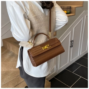 Detail shot of a dark brown woven texture handbag with golden metallic twist lock buckle