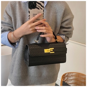 Close-up of black woven leather handbag featuring a premium gold twist lock and handle