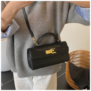 Detail of black woven handbag with gold clasp worn by a model in casual grey knitwear