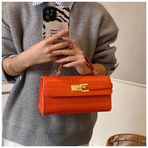 Macro detail of orange woven handbag showing intricate texture and gold metal lock clasp