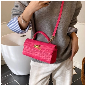 Detail view of woven leather texture and golden twist lock on a rose pink handbag
