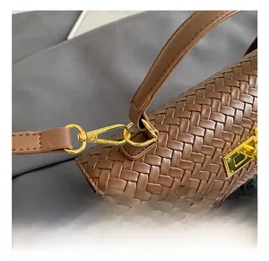 Close-up of golden metal hook and brown woven leather texture on a crossbody bag