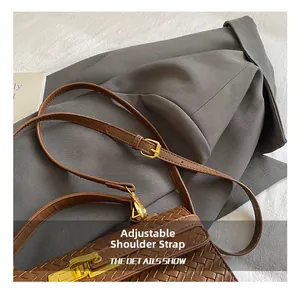 Detail of adjustable strap and golden buckle on brown woven leather crossbody bag