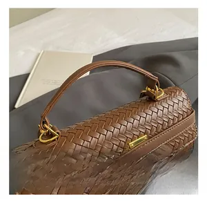 Close-up of brown woven leather handbag showing sturdy top handle and gold metal lock detail