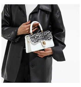Close-up of white PU leather handbag featuring leopard print flap and gold round twist lock