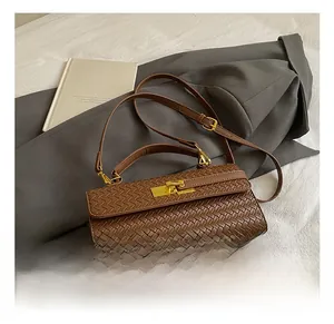 Detailed close-up of dark brown woven texture handbag with golden clasp and long strap