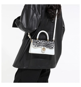 Detail of white leather shoulder bag featuring a leopard print flap and golden lock