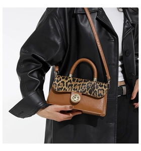 Detail of leopard print flap bag with gold twist lock and adjustable crossbody strap