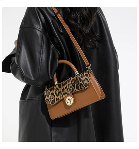Detail of brown leather handbag featuring leopard print patchwork and gold metal twist lock