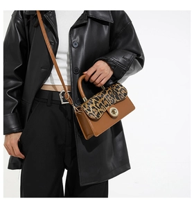 Close-up of leopard print flap bag with gold twist lock and smooth brown leather texture