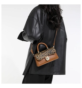 Detail of leopard print flap and gold twist lock on brown leather crossbody bag