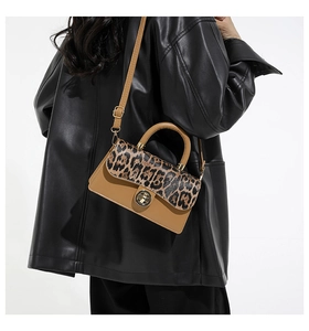 Detail of leopard print flap shoulder bag with gold twist lock and brown leather handle