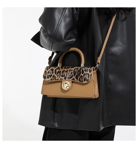 Detail of leopard print flap bag with gold twist lock and brown leather strap on model