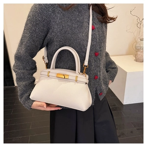 Detailansicht der weißen Handtasche mit Litschi-Muster und glänzenden goldenen Beschlägen