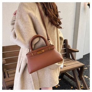 Detail einer braunen Handtasche aus Leder mit Litschimuster und eleganter goldener Schließe