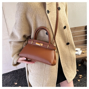 Detail der braunen Lederhandtasche mit Lychee-Muster und goldenem Verschluss am Mantel