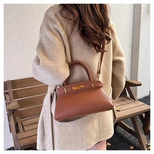 Detailaufnahme der braunen Lederhandtasche mit Lychee-Muster und goldenem Metallschloss
