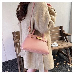 Details einer rosa Handtasche mit Litschi-Struktur, Goldverschluss und Schultergurt