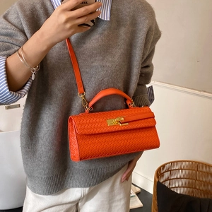 Bright orange woven leather crossbody bag with gold buckle worn by model