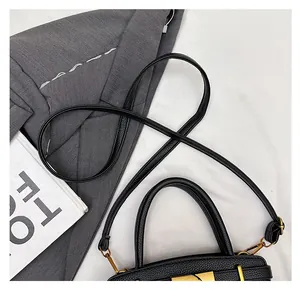 Detail der schwarzen Handtasche aus Leder mit goldener Schnalle und verstellbarem Riemen