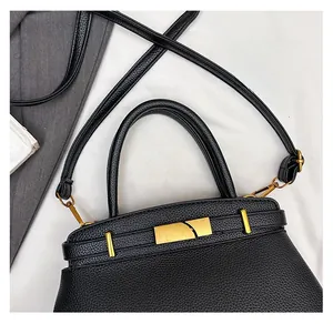 Detail der schwarzen Handtasche aus Leder mit goldener Schließe und stabilem Tragegriff