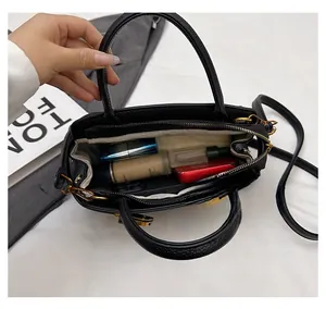 Detail der schwarzen Handtasche mit Lederstruktur, geräumigem Innenfach und Zubehör