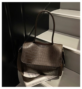 Detail of dark brown faux crocodile leather texture on a vintage tote bag with flap