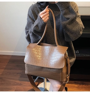 Close-up of brown crocodile pattern leather handbag with wide shoulder strap