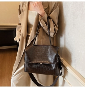 Detail of dark brown crocodile pattern tote with versatile straps on a stylish model