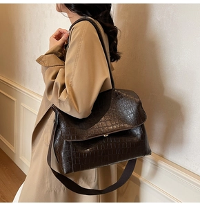 Detail of large dark brown tote bag with crocodile pattern and wide shoulder strap