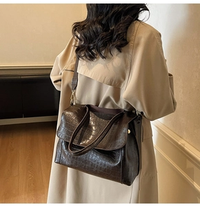Brown crocodile embossed tote bag styled with a trench coat for a chic commute look