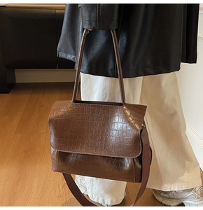 Brown crocodile embossed tote bag detail with wide strap and minimalist flap closure