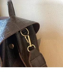 Detail of dark brown crocodile embossed leather bag with premium gold metal hardware hooks